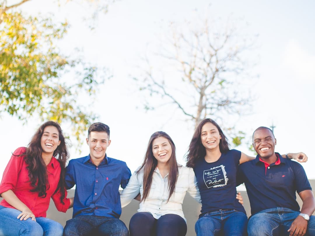 Five students sitting together on a bench outdoors
