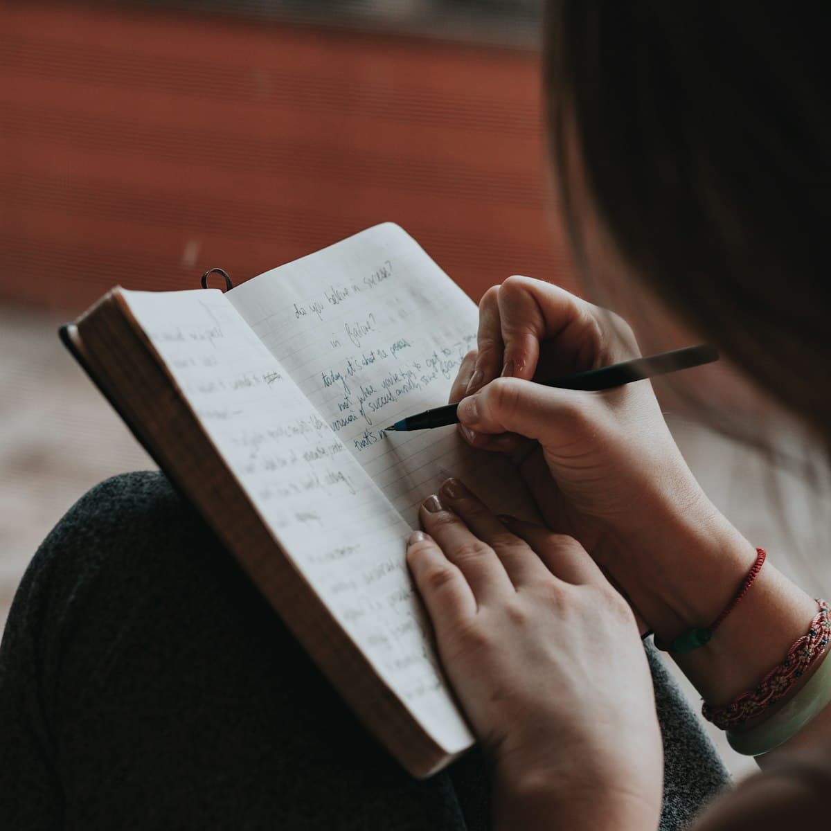A student writing notes by hand in a ruled notebook